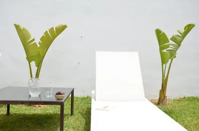 a chair and a table with a vase and a plant at Villa Puntalejo por Living Cadiz in Conil de la Frontera