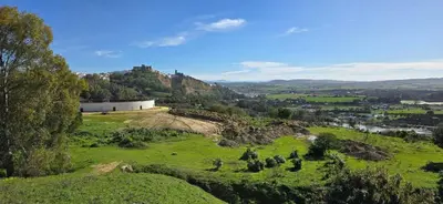 a green hill with a castle on top of it at La casa de curro in Arcos de la Frontera
