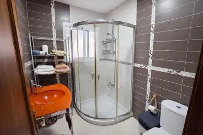 a bathroom with a shower with an orange stool in it at Chalet Amanecer Chiclana in Novo Sancti Petri