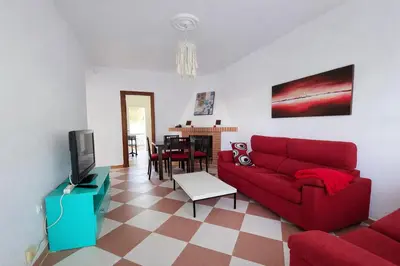 a living room with a red couch and a tv at Chalet Amanecer Chiclana in Novo Sancti Petri