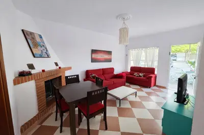 a living room with a red couch and a table at Chalet Amanecer Chiclana in Novo Sancti Petri