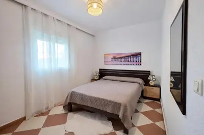 a white bedroom with a bed and a window at Chalet Amanecer Chiclana in Novo Sancti Petri