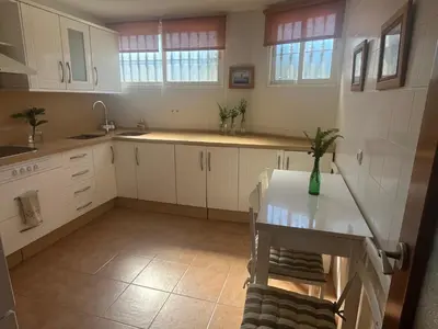 a kitchen with white cabinets and a table with a vase on it at La Balconera Apartamento junto a la playa in Novo Sancti Petri