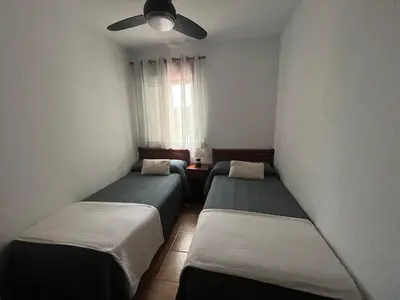 three beds in a room with a window at La Balconera Apartamento junto a la playa in Novo Sancti Petri