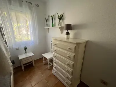 a bedroom with a dresser with a lamp and flowers on it at La Balconera Apartamento junto a la playa in Novo Sancti Petri