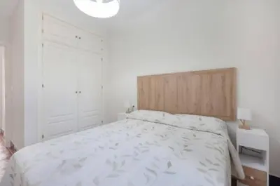 a bedroom with a white bed with a wooden headboard at Townhouse in La Loma de Sancti Petri , 3 Bedrooms, Pool, Pedal Tennis in Novo Sancti Petri