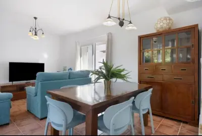 a living room with a wooden table and blue chairs at Townhouse in La Loma de Sancti Petri , 3 Bedrooms, Pool, Pedal Tennis in Novo Sancti Petri