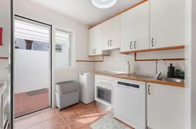 a kitchen with white cabinets and a sink and a refrigerator at Townhouse in La Loma de Sancti Petri , 3 Bedrooms, Pool, Pedal Tennis in Novo Sancti Petri