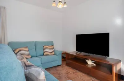 a living room with a blue couch and a flat screen tv at Townhouse in La Loma de Sancti Petri , 3 Bedrooms, Pool, Pedal Tennis in Novo Sancti Petri