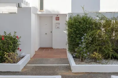 a white door in a white building with flowers at Townhouse in La Loma de Sancti Petri , 3 Bedrooms, Pool, Pedal Tennis in Novo Sancti Petri