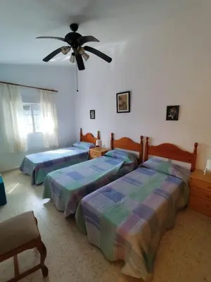 a bedroom with three beds and a ceiling fan at Beachside Duplex Chalet -800 m to La Barrosa Beach in Novo Sancti Petri