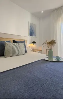 a bedroom with a large bed with a blue rug at Apartamento Marea en primera línea de playa en La Barrosa con vistas al mar in Novo Sancti Petri