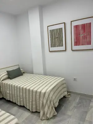 a bedroom with a bed and two pictures on the wall at Apartamento Marea en primera línea de playa en La Barrosa con vistas al mar in Novo Sancti Petri