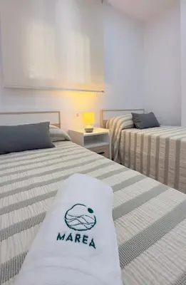 a room with two beds with a mara sign on them at Apartamento Marea en primera línea de playa en La Barrosa con vistas al mar in Novo Sancti Petri