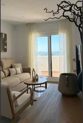 a living room with a couch and a table at Apartamento Marea en primera línea de playa en La Barrosa con vistas al mar in Novo Sancti Petri