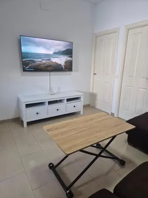 a living room with a table and a tv on the wall at Apartamento Bahia de Cadiz in Puerto Real
