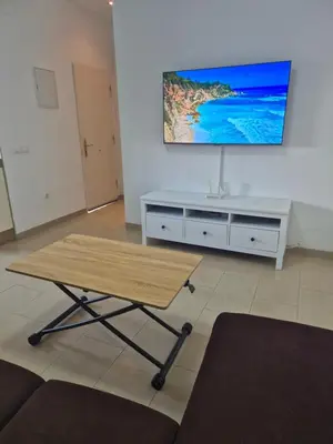 a living room with a table and a tv on a wall at Apartamento Bahia de Cadiz in Puerto Real