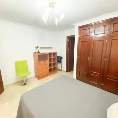 a bedroom with a bed and a green chair at Bulerías de Cádiz by Gades Gestión in Cádiz