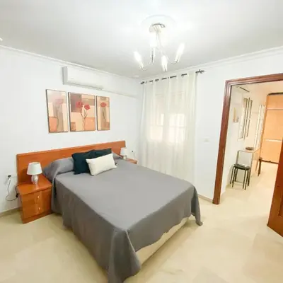 a bedroom with a large bed and a chandelier at Bulerías de Cádiz by Gades Gestión in Cádiz