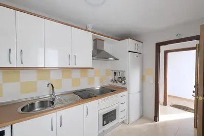 a kitchen with white cabinets and a sink at Ático luminoso con terraza de 28 m con plaza garaje a 9mn del centro in Sanlúcar de Barrameda