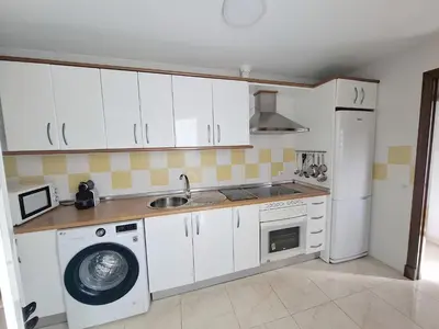 a kitchen with white cabinets and a washing machine at Ático luminoso con terraza de 28 m con plaza garaje a 9mn del centro in Sanlúcar de Barrameda