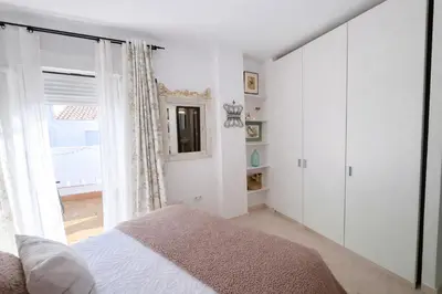 a white bedroom with a bed and a window at Ático luminoso con terraza de 28 m con plaza garaje a 9mn del centro in Sanlúcar de Barrameda