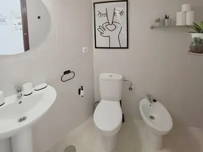 a white bathroom with a toilet and a sink at Ático luminoso con terraza de 28 m con plaza garaje a 9mn del centro in Sanlúcar de Barrameda