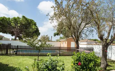 a fence in a yard with trees and flowers at Hogar Lowill in Chiclana de la Frontera