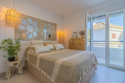 a bedroom with a large bed and a large window at Coqueto apartamento en primera linea de playa in Novo Sancti Petri