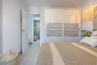 a bedroom with a large bed and a bathroom at Coqueto apartamento en primera linea de playa in Novo Sancti Petri