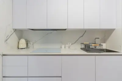 a white kitchen with white cabinets and a sink at Coqueto apartamento en primera linea de playa in Novo Sancti Petri