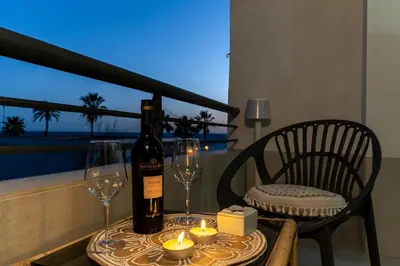 a bottle of wine sitting on a table with candles and wine glasses at Coqueto apartamento en primera linea de playa in Novo Sancti Petri