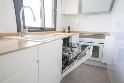 a white kitchen with a dishwasher and a sink at Charming Apartment with Private Terrace in Sanlúcar de Barrameda