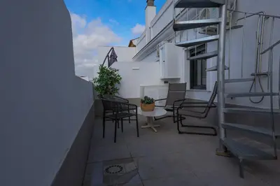 a balcony with chairs and a table on a building at Charming Apartment with Private Terrace in Sanlúcar de Barrameda