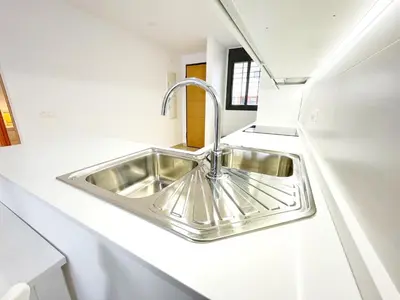 a stainless steel sink in a white kitchen at El Arrecife - Apartamento a 2 minutos de la playa en El Puerto de Santa María in El Puerto de Santa María