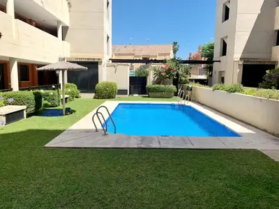a swimming pool in the yard of a building at El Arrecife - Apartamento a 2 minutos de la playa en El Puerto de Santa María in El Puerto de Santa María