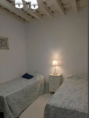 a bedroom with two beds and a lamp on a night stand at La Casita de Cai in Cádiz
