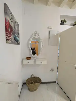 a white bathroom with a mirror and a basket at La Casita de Cai in Cádiz