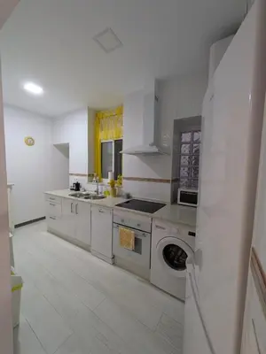 a white kitchen with a stove and a sink at La Casita de Cai in Cádiz