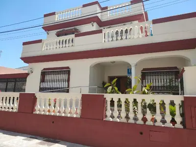 a white and red building with a balcony at HOTEL Guadalupe in Chipiona
