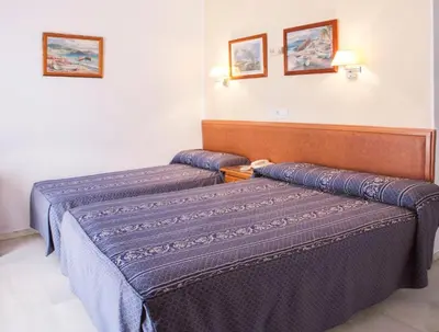 two beds in a hotel room with blue sheets at HOTEL Guadalupe in Chipiona