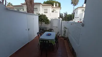 a table and chairs on a patio with a white fence at Apartamento en La Barrosa, Chiclana de la Frontera in Novo Sancti Petri