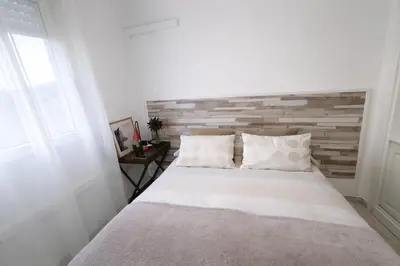 a bedroom with a white bed with a wooden headboard at Apartamento 3 dormitorios con garaje y wifi gratis a pocos minutos del centro de Jerez in Jerez de la Frontera