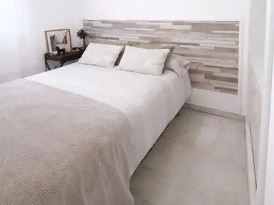 a bedroom with a large white bed and a brick wall at Apartamento 3 dormitorios con garaje y wifi gratis a pocos minutos del centro de Jerez in Jerez de la Frontera