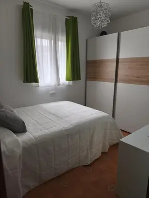 a bedroom with a bed and a window with green curtains at El Refugio de MELKART in San Fernando