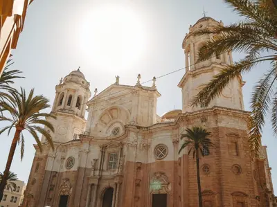 a church with palm trees in front of it at Hidden Gem PLAYA DE SANTA MARÍA SUITES by ApartmentsinCadiz in Cádiz