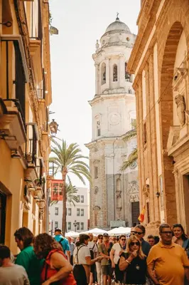 a crowd of people walking down a street with a clock tower at Hidden Gem PLAYA DE SANTA MARÍA SUITES by ApartmentsinCadiz in Cádiz