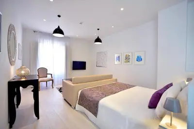 a white bedroom with a large bed and a desk at El Armador Casa Palacio by Luxury Suites Cádiz in Cádiz