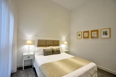 a white bedroom with a large bed and two lamps at El Armador Casa Palacio by Luxury Suites Cádiz in Cádiz