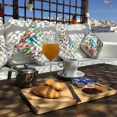 a table with a glass of orange juice and a tray of bread at Hotel Posada de las Cuevas in Arcos de la Frontera